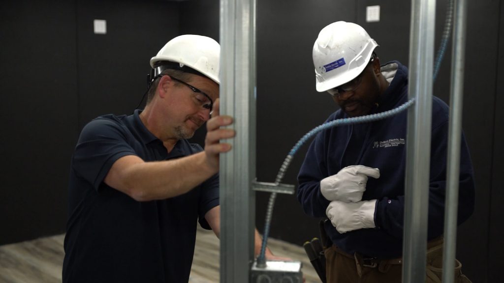 Two electricians working on a job indoors